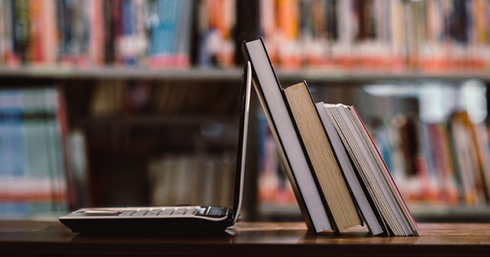 laptop computer and book on workplace in library room,Education